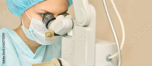 Pretty doctor woman portrait. Ophthalmology laser microscope operation. Clinic room. Patient eye treatment. Myopia and cataract removal