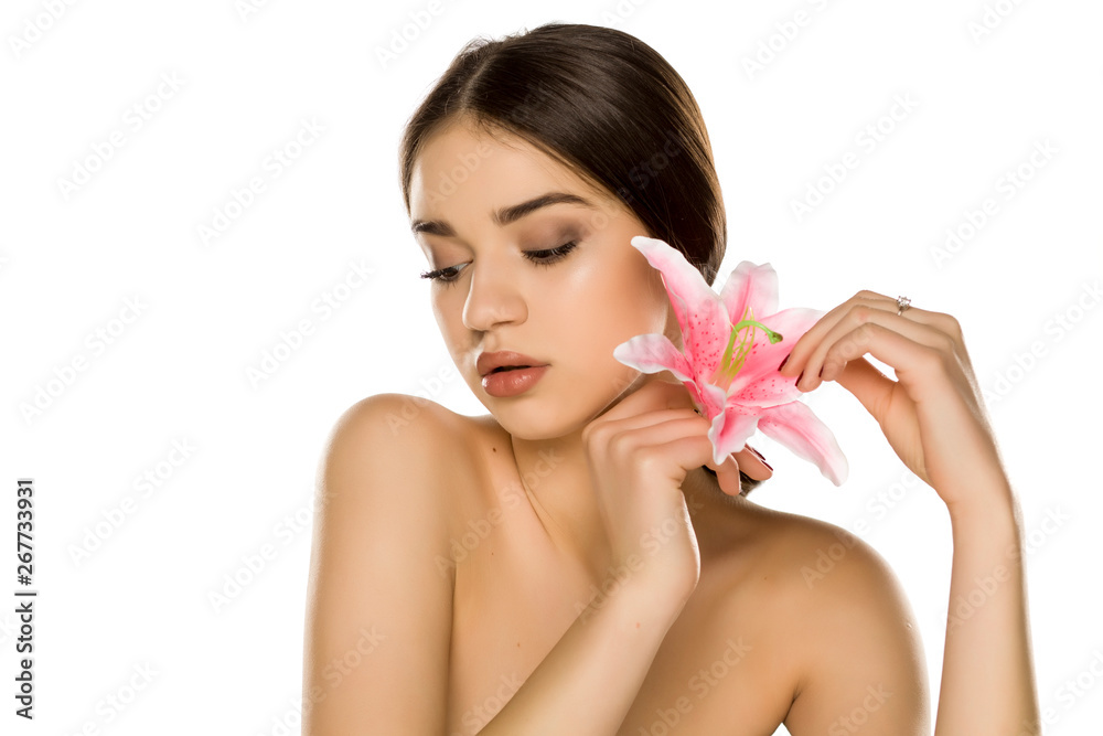 Young woman with makeup posing with orchid on white background Young woman with makeup posing with orchid on white background
