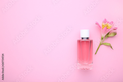 Bottle of perfume with flowers on pink background