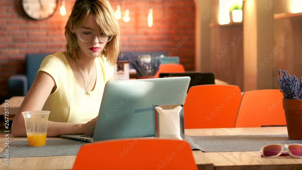 Young woman using laptop while sitting in cafe, 4K Young woman using laptop while sitting in cafe, 4K