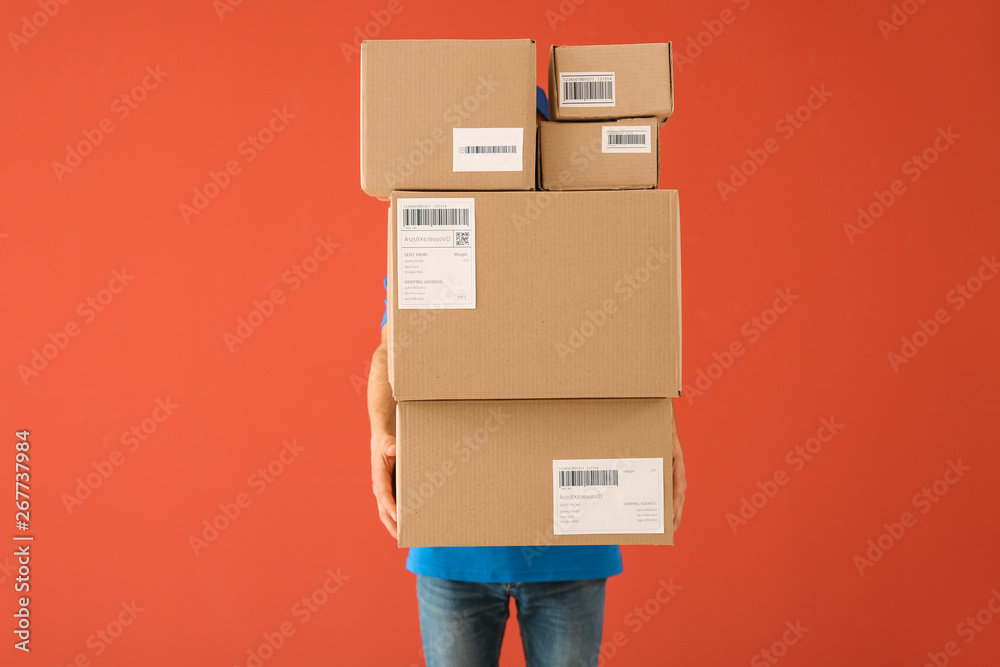 Delivery man with boxes on color background - obrazy, fototapety, plakaty 