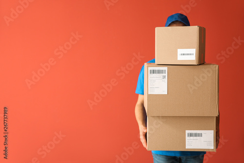 Delivery man with boxes on color background photo