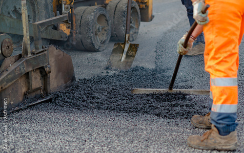 Worker regulate tracked paver laying asphalt heated to temperatures above 160 ° pavement on a runway