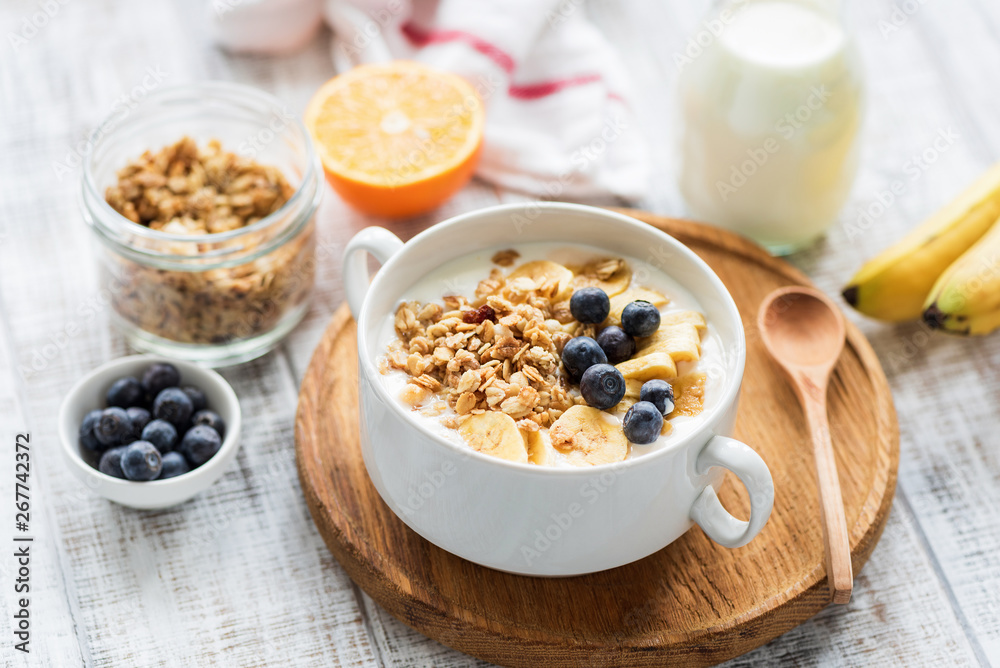 Granola bowl with fruits and milk on a white wooden table. Concept of weight loss, dieting, healthy eating and wellbeing Granola bowl with fruits and milk on a white wooden table. Concept of weight loss, dieting, healthy eating and wellbeing