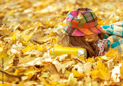 Happy autumn travel woman. Beautiful woman wearing bright clothes with yellow suitcase