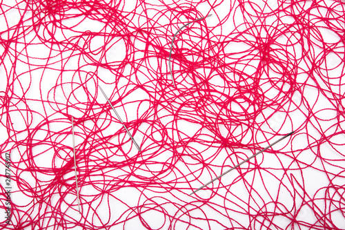 A ball of red thread and sewing needles on a white background
