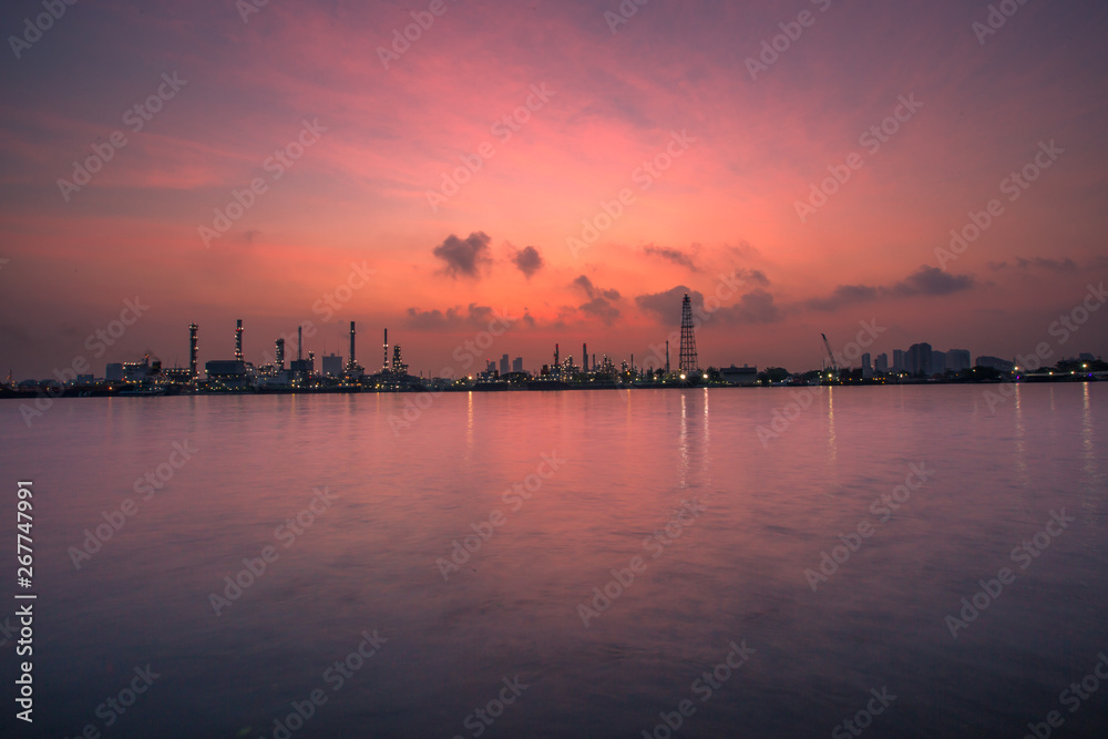 Fototapeta premium The blurred background of nature along the river, with views of the cargo ship, oil refinery, sunrise and beautiful sky in the morning