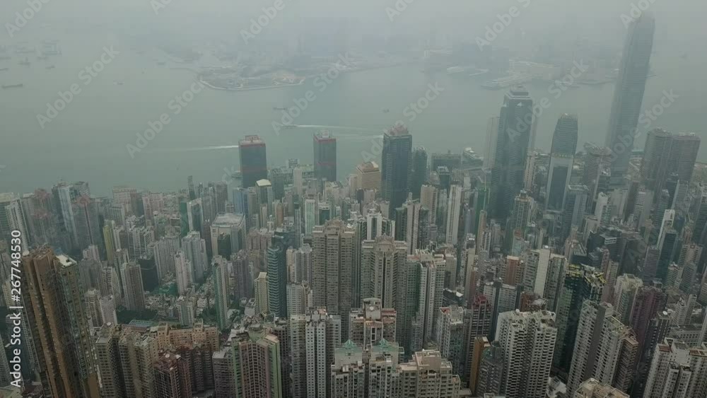 Aerial dolly out of foggy dramatic Hong Kong skyline and Victoria harbour