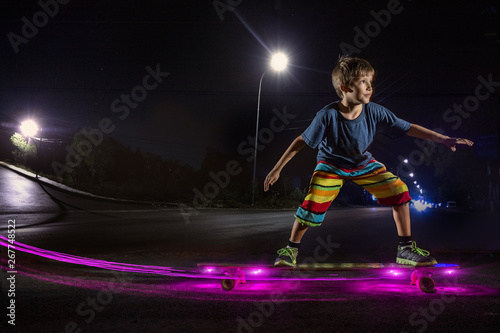 Kid skating with light in a night park photo