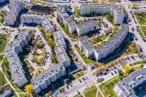 Aerial city view with crossroads and roads, houses, buildings, parks and parking lots.