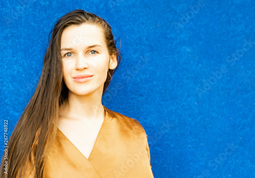 young beautiful girl in a golden dress enjoying the last rays of the sun at sunset
