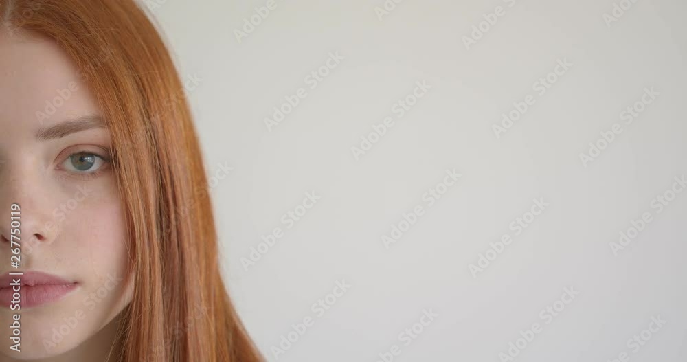 Half face portrait of beautiful ginger model watching calmly and intently into camera on white background. Half face portrait of beautiful ginger model watching calmly and intently into camera on white background.
