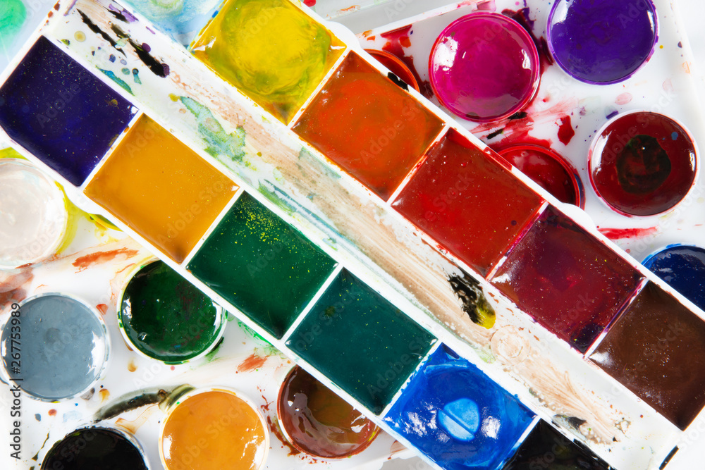 A set of children's paints in round, rectangular forms close-up. Original creative background
