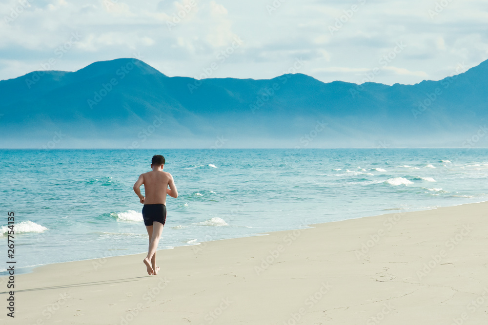 A man performs a morning workout. Running along the sandy beach along the coastline. Copy space for text. Vietnam
