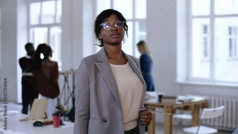 Portrait of serious young African entrepreneur business woman in eyeglasses and formal suit posing at modern office. Portrait of serious young African entrepreneur business woman in eyeglasses and formal suit posing at modern office.
