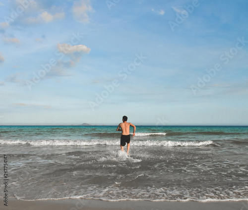 Obraz na płótnie A man runs into the water of the tropical sea. View from the back. Copy space for text. Vietnam w salonie