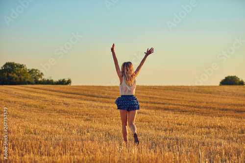 Fototapeta Naklejka Na Ścianę i Meble -  Cute young woman jumping in a wheat field.