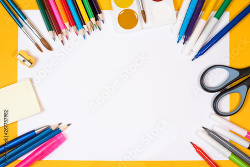 Back to school. Children's creativity. Colored pencils, felt-tip pens, brushes and paints, scissors on a yellow background