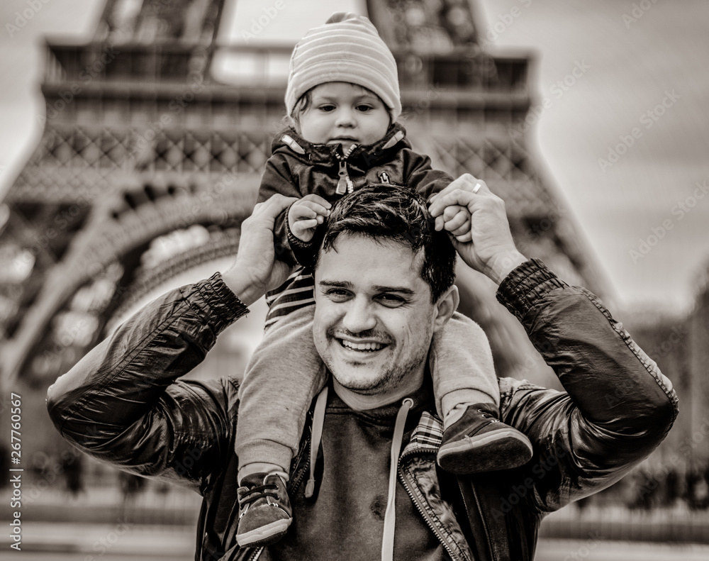 father with baby boy on shoulders with Eiffel tower