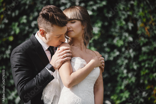 Closeup Portrait of wedding bride and groom with bouquet posing. Bridal couple, Happy Newlywed woman and man hugging. Bride and groom