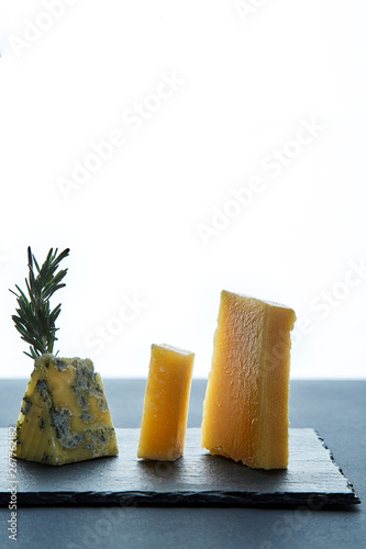 Several pieces of cheese beside on white background and black dish.
