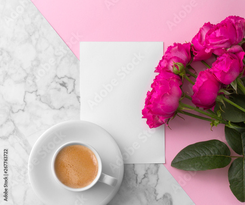 Pink roses with blank greeting card and coffee cup over pink marble background. 