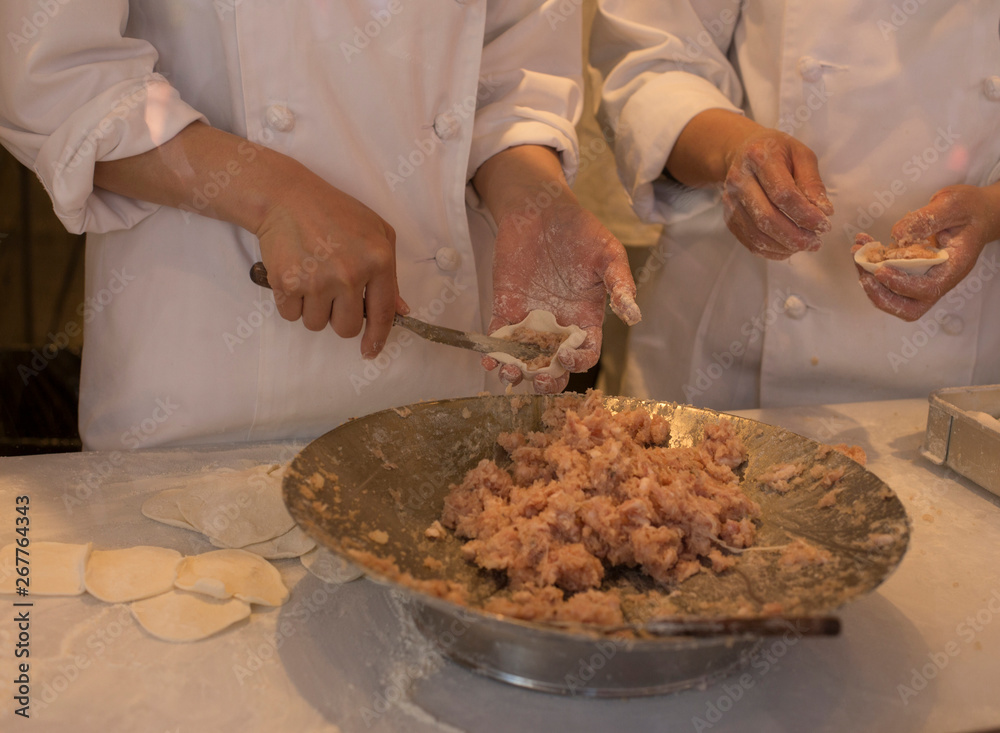 Hands of chefs stuffing meat for the grilled rice dumplings at Chinatown in Kobe in Japan