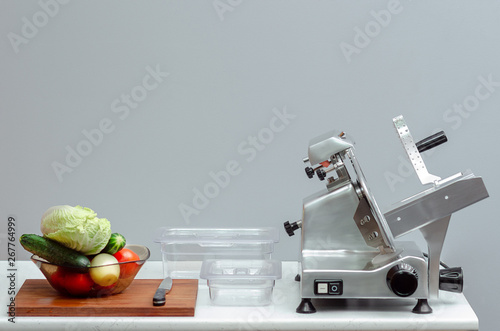 slicer for cutting food on the table with vegetables and canteens for storage
