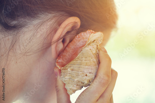 young happy woman listening to seashell
