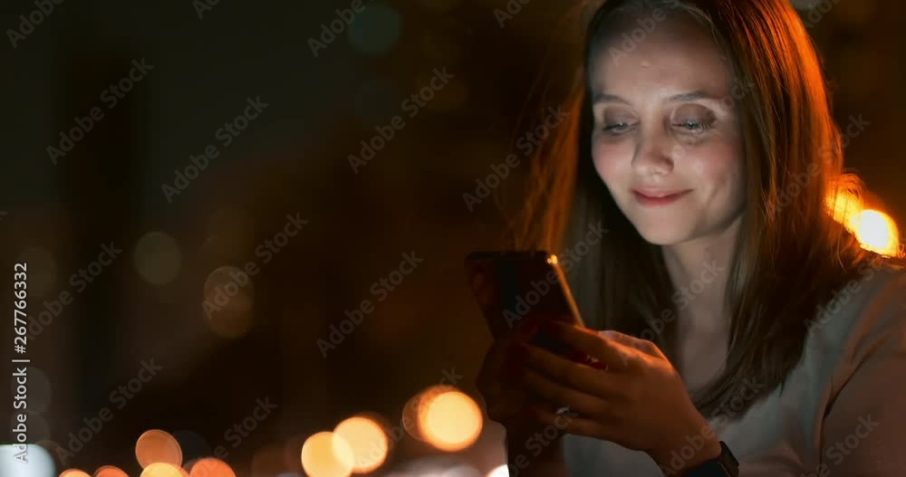 Young woman sitting at night in the city with smartphone Young woman sitting at night in the city with smartphone