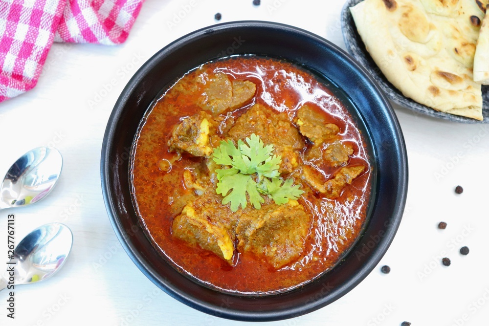 Mutton do Pyaza or Indian lamb Curry with some spices like black pepper, red chili powder, turmeric and garnished with coriander leaves served with Naan or Roti on wooden table Mutton do Pyaza or Indian lamb Curry with some spices like black pepper, red chili powder, turmeric and garnished with coriander leaves served with Naan or Roti on wooden table