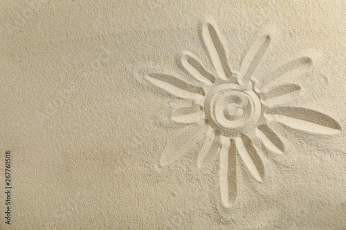 Sun drawing on clear sea sand, space for text and top view. Summer vacation background