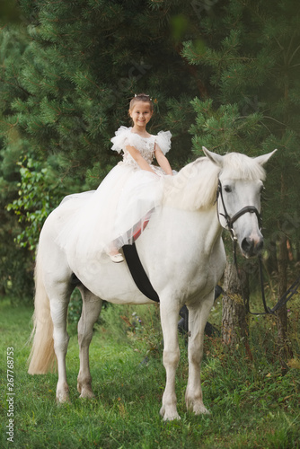 happy little princess on white horse in the forest