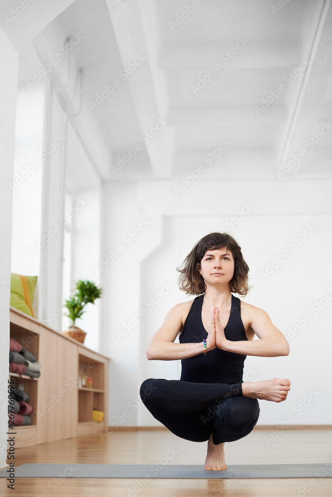 Front portrait view of young woman practicing yoga, balancing on one leg. Yogi seeking enlightenment through meditation, relaxing, performing yoga routine. Healthy body and spirit. Copy space on top