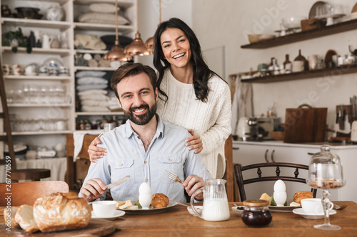 Portrait of young european couple eating at table while having breakfast in kitchen at home