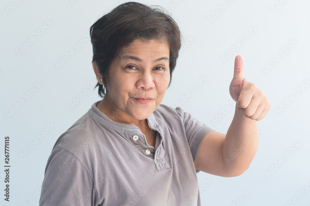 middle aged asian woman giving yes, ok, approving thumb up gesture middle aged asian woman giving yes, ok, approving thumb up gesture