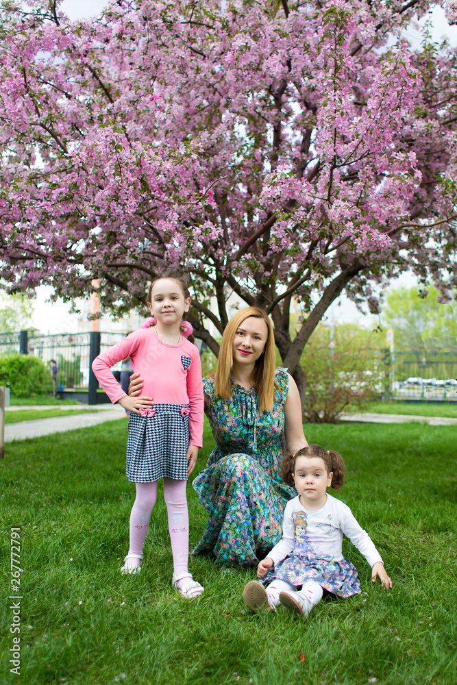 Obraz premium funny girls walking on the lawn with her mother. Sisters play together with mom. maternal care. happy family