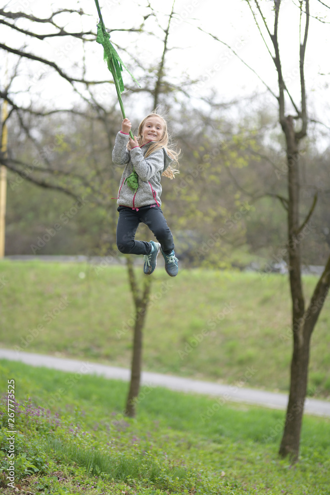 Happy child girl laughing and swinging on a swing