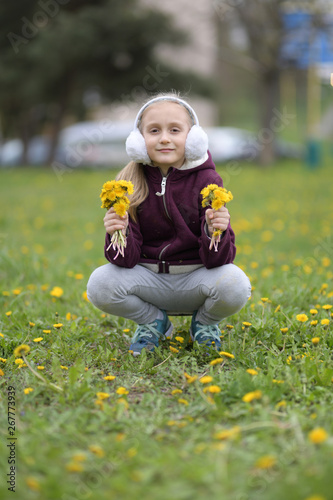 little child playing in the park with dandelions