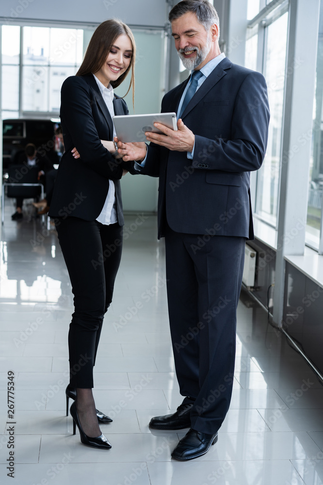 Business People standing in the office and looking at a tablet. Business People standing in the office and looking at a tablet.