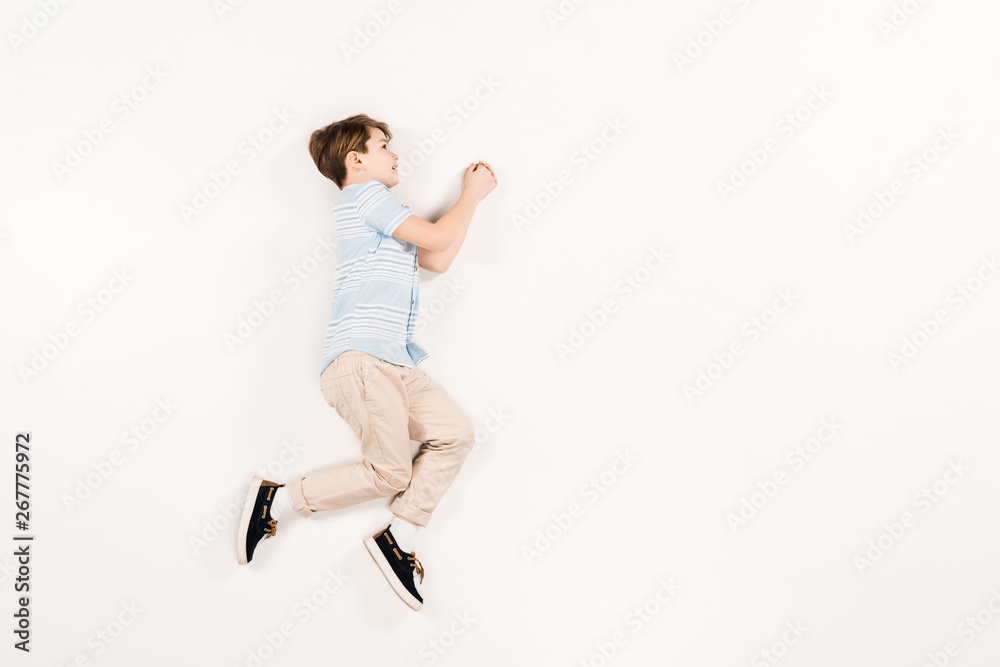 happy and cute child lying and gesturing on white