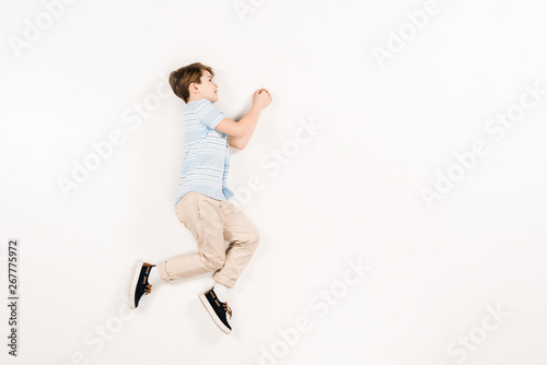 happy and cute child lying and gesturing on white