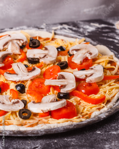 young woman in a gray aprong prepares a vegetarian pizza