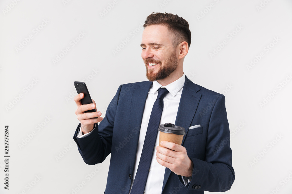 Happy businessman posing isolated over white wall background drinking coffee using mobile phone. Happy businessman posing isolated over white wall background drinking coffee using mobile phone.