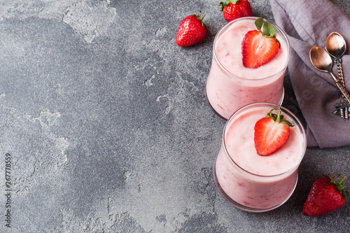 Homemade yogurt with fresh strawberries in glasses on a dark concrete background. Selective focus. Copy space.