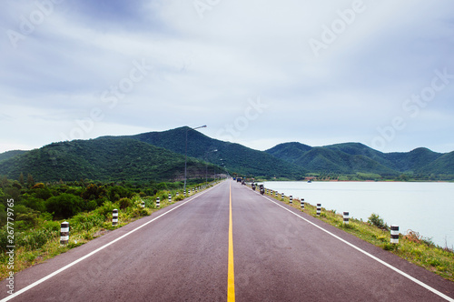 Lake side road with cloudy summer sky and mountain