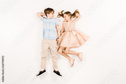 top view of cheerful kids looking at each other on white