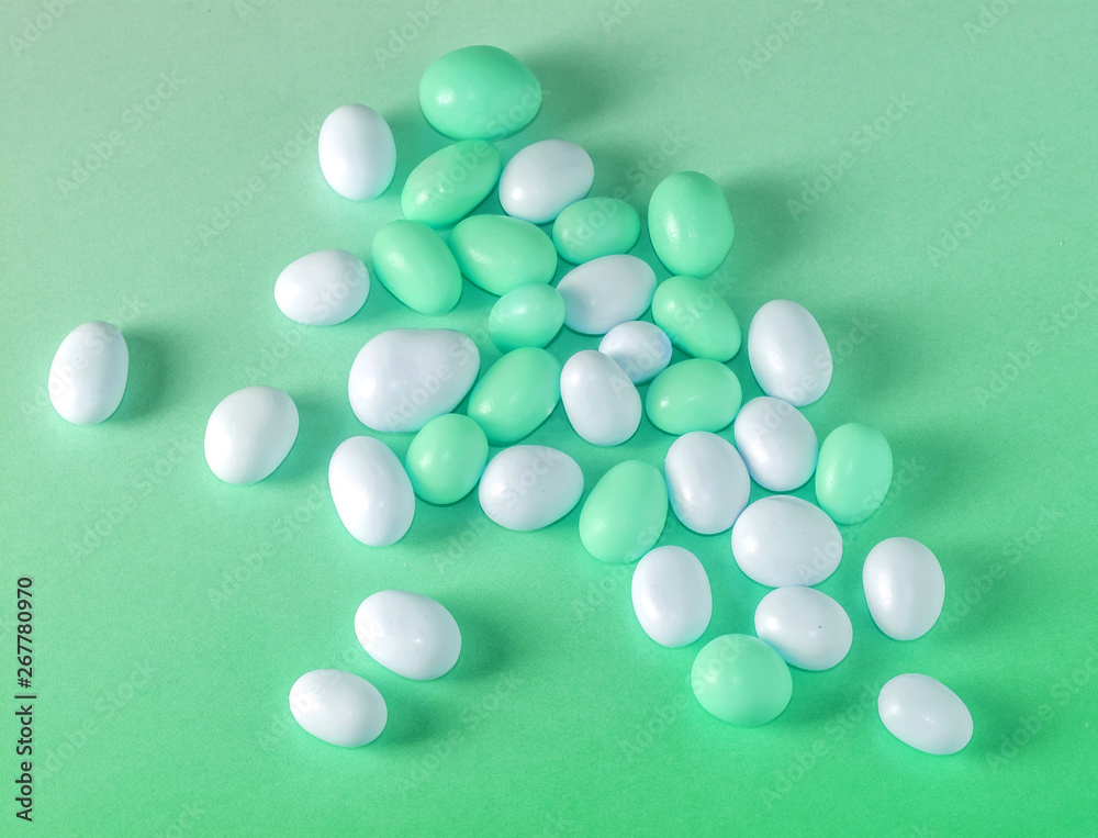 Assorted fullcolor green and white candy dragees on green background.