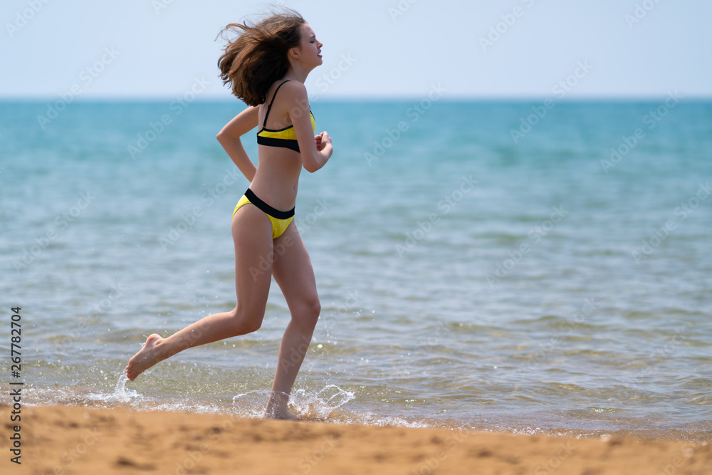 Fototapeta premium Fit slender young woman jogging on a beach