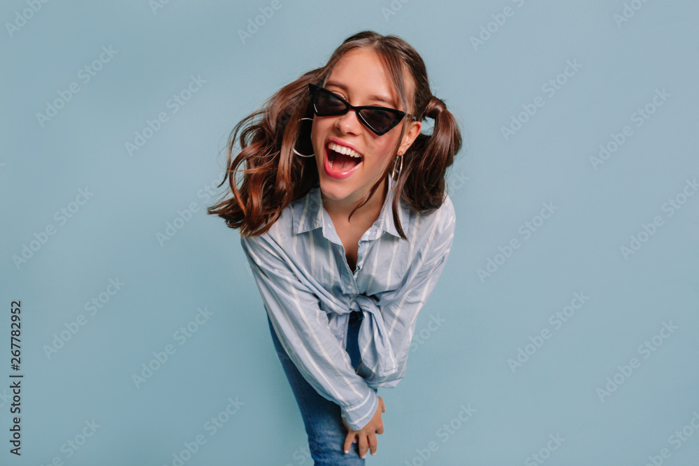 Exited lovable woman with happy emotions and wonderful smile posing at camera over blue background Exited lovable woman with happy emotions and wonderful smile posing at camera over blue background